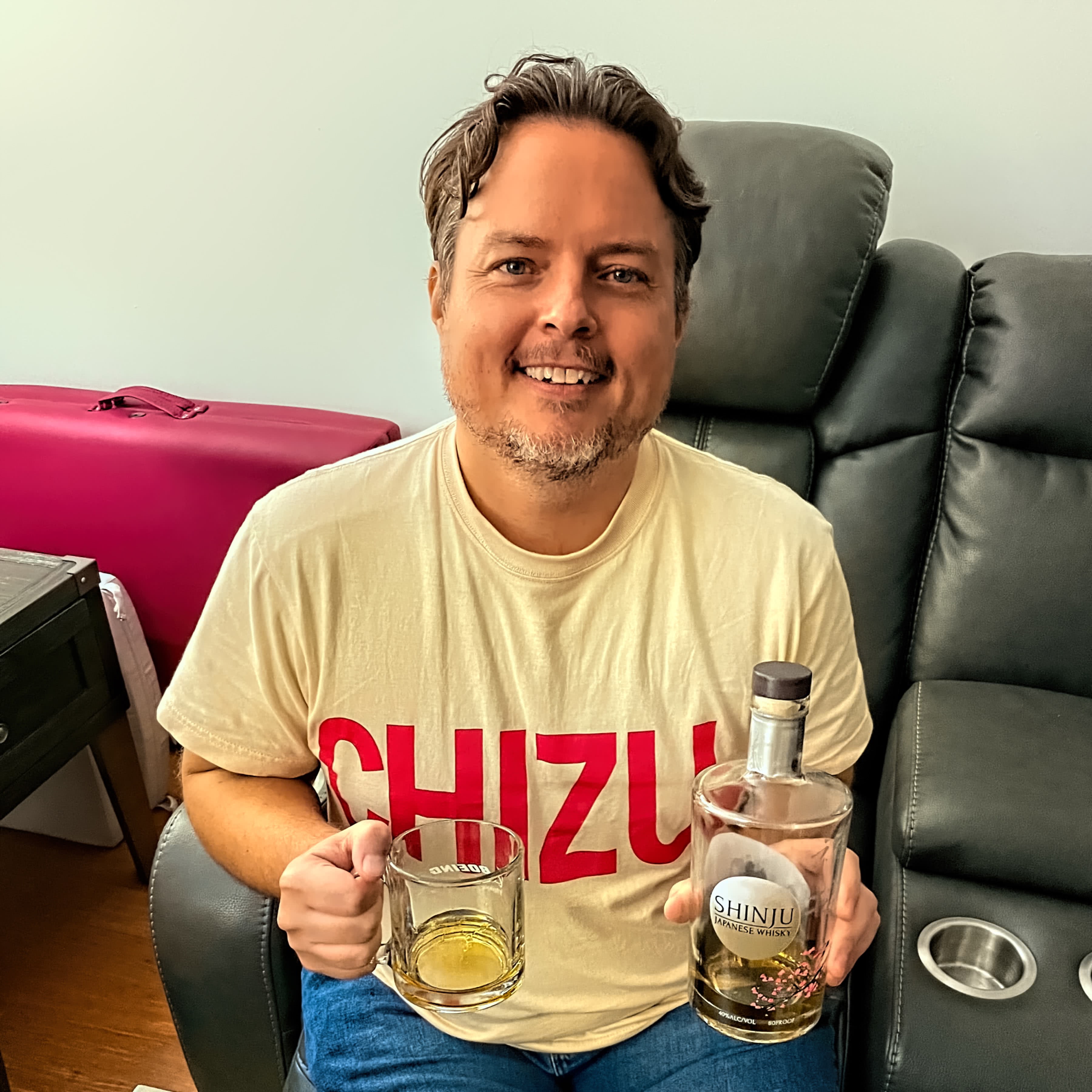 Neil holds a glass and bottle of Japanese whisky while wearing his Chizu shirt in Columbia, MD, US