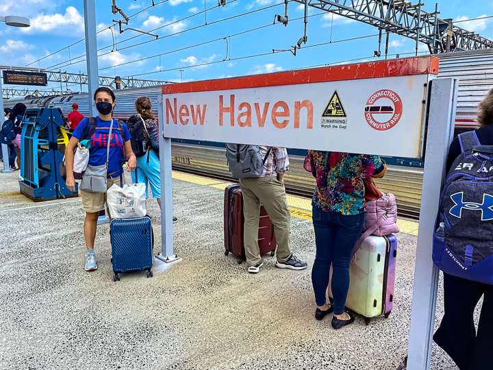 Maria stands next to an Amtrak station sign while wearing her Chizu shirt in New Haven, CT, US